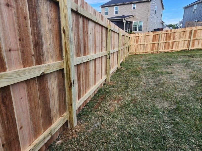 A wooden fence in a backyard with a house in the background.