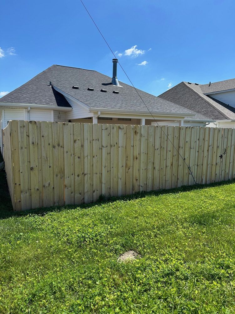 A wooden fence is in the backyard of a house.