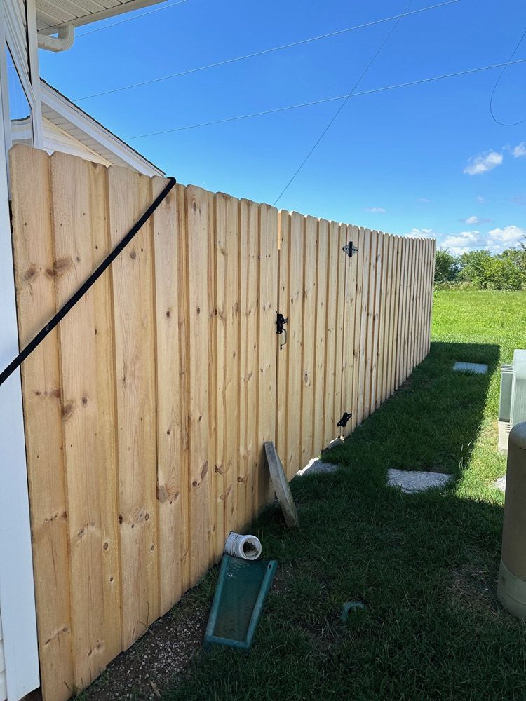 A wooden fence is sitting in the grass next to a house.