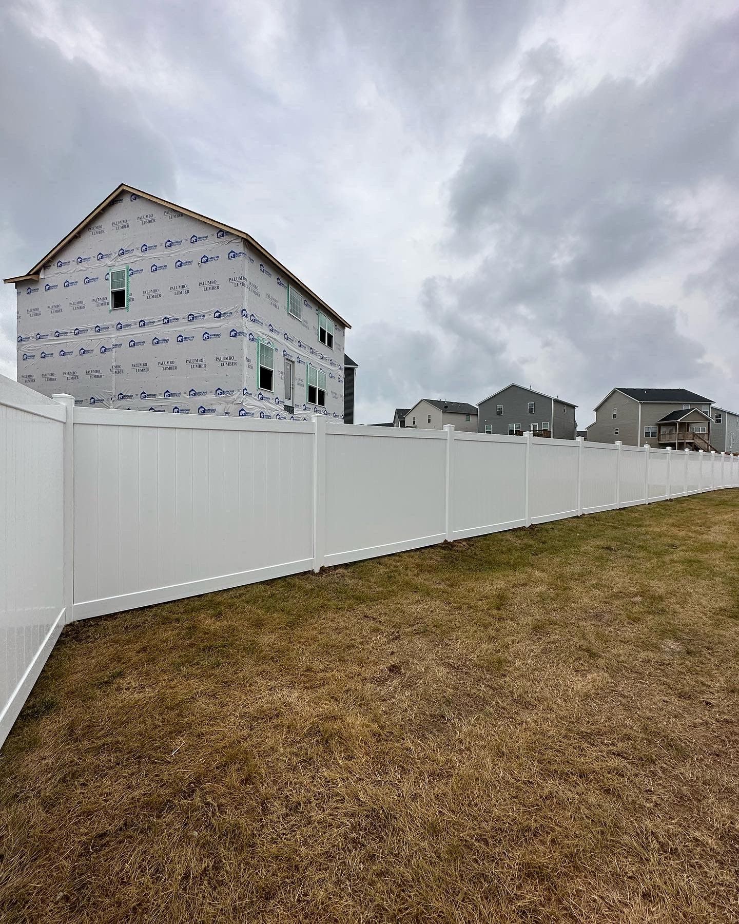 a white fence surrounds a yard with a house under construction in the background — Lexington, KY — Chafin Fence LLC