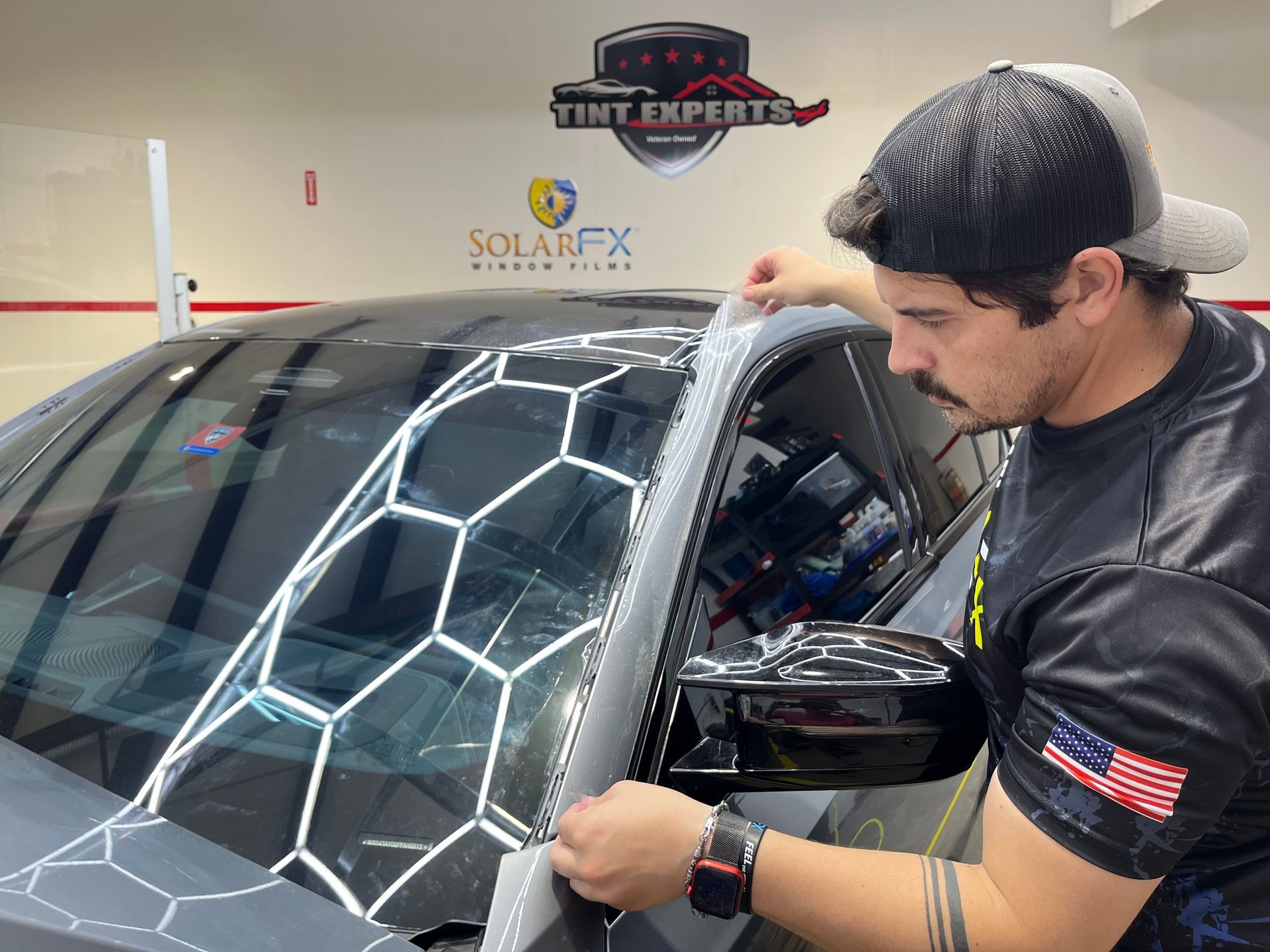 A man is applying tint to the windshield of a car.