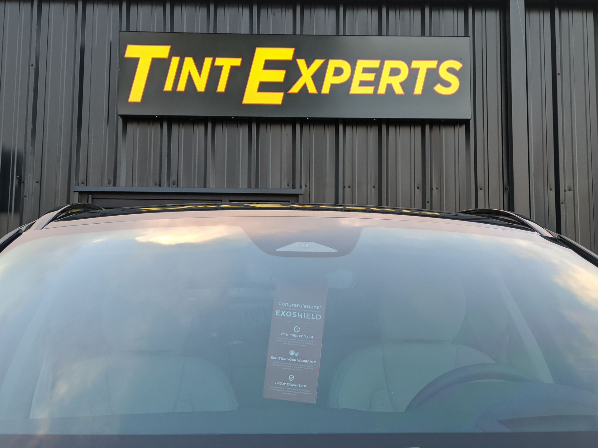 A car is parked in front of a tint experts sign.