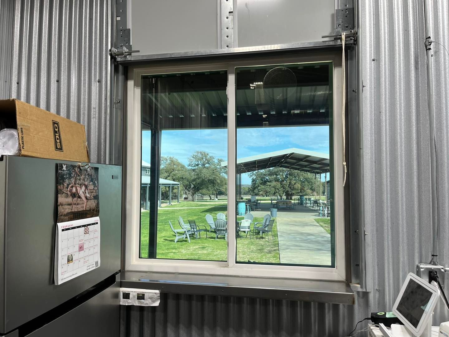 A window in a metal building with a view of a park.