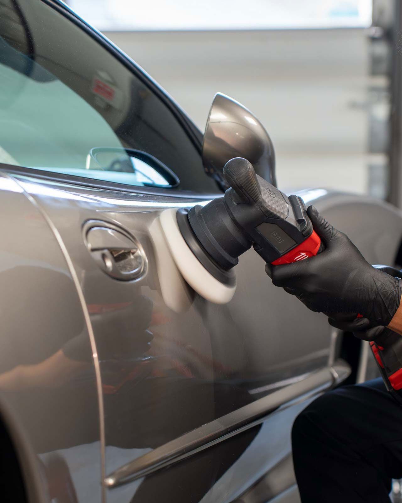 A person is polishing a car with a machine.