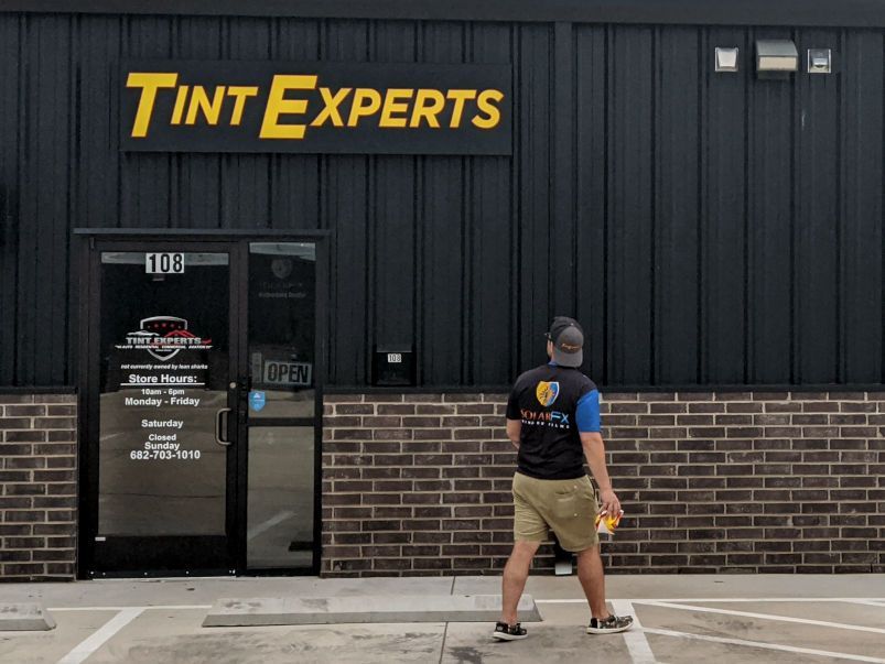 A man is walking in front of a tint experts store