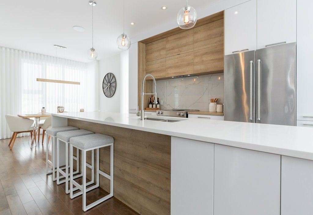 Une cuisine avec armoires blanches, armoires en bois, électroménagers en acier inoxydable et un grand îlot.