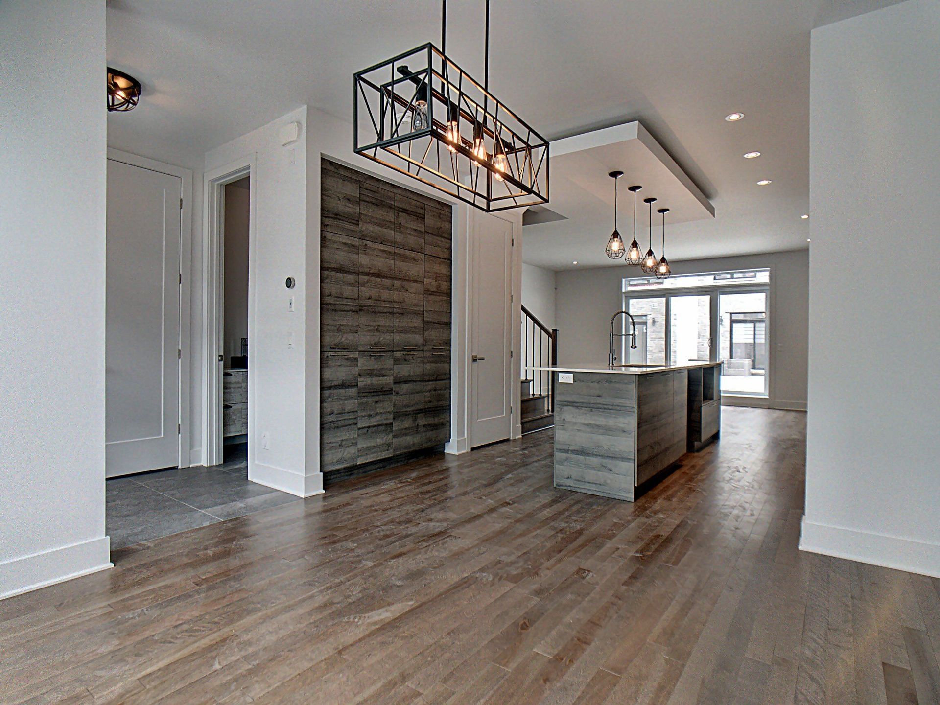 Une pièce vide avec du parquet et un lustre suspendu au plafond