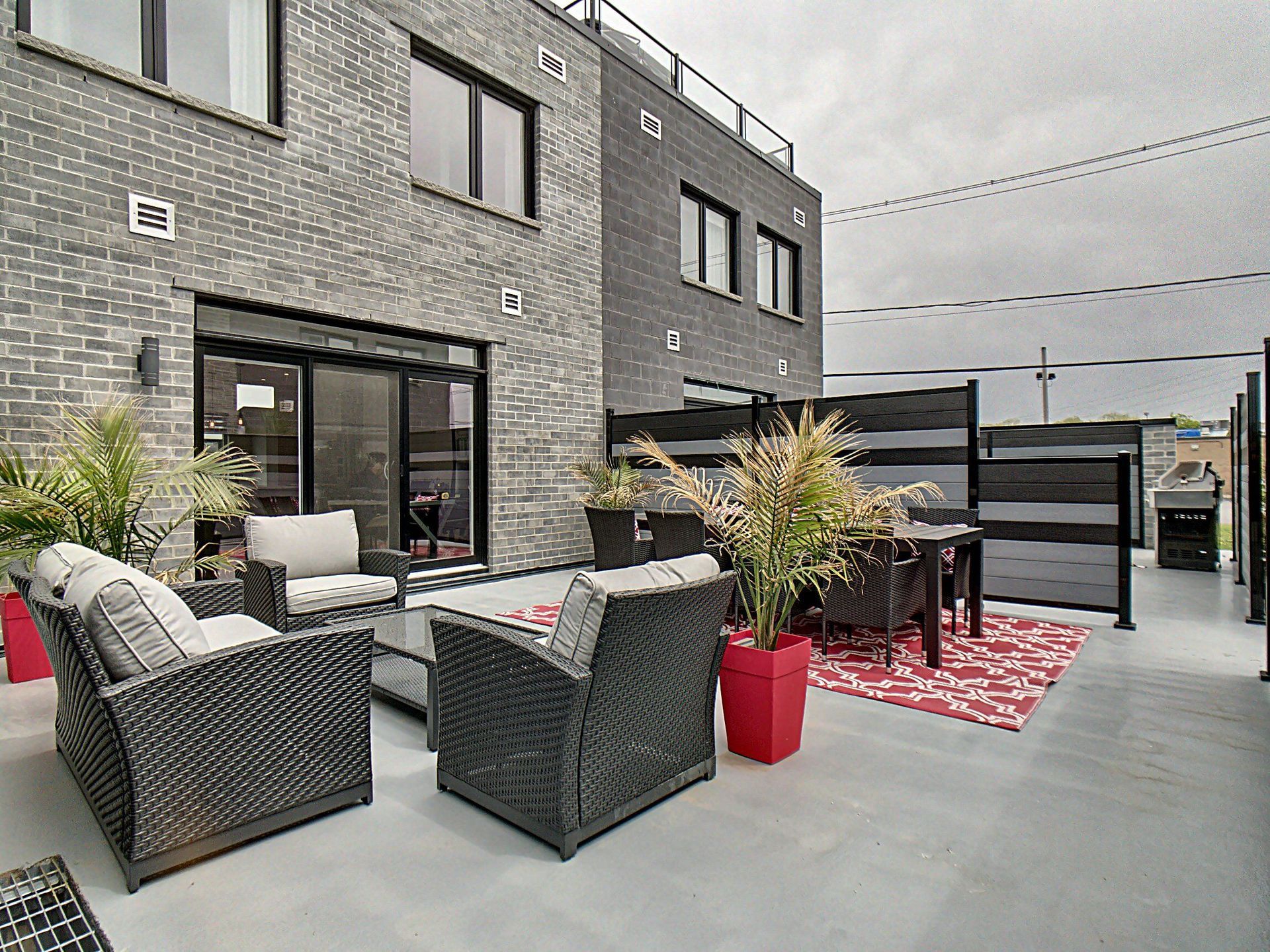 Un patio avec des meubles en osier et une table et des chaises devant un bâtiment en brique.