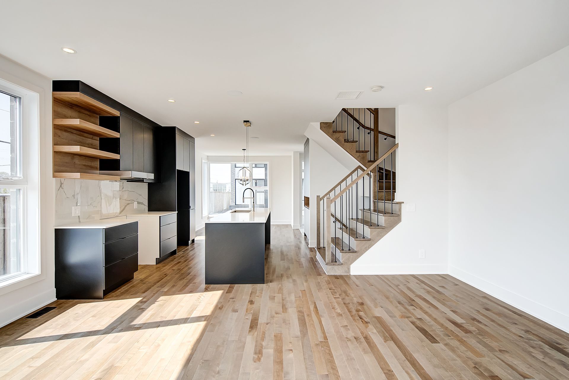 Une pièce vide avec parquet et escaliers dans une maison.