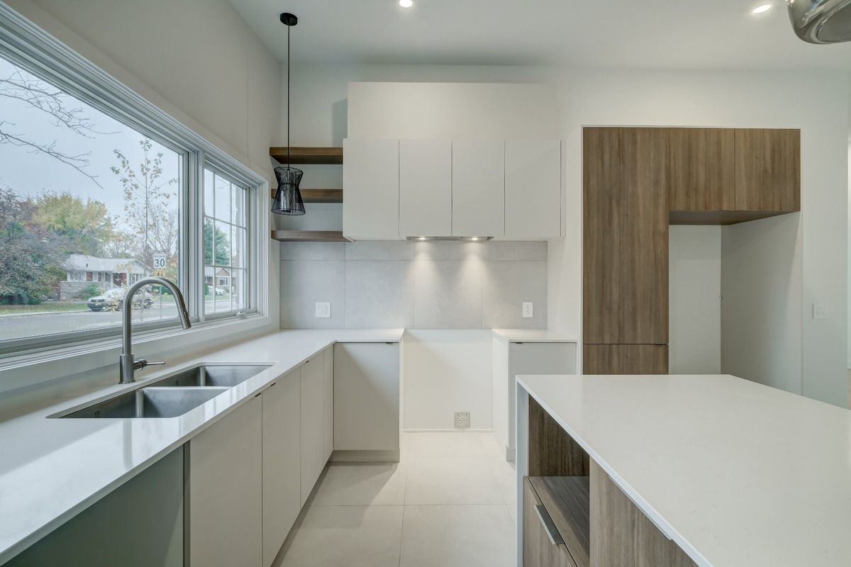 Une cuisine avec des armoires blanches, un évier et une fenêtre.