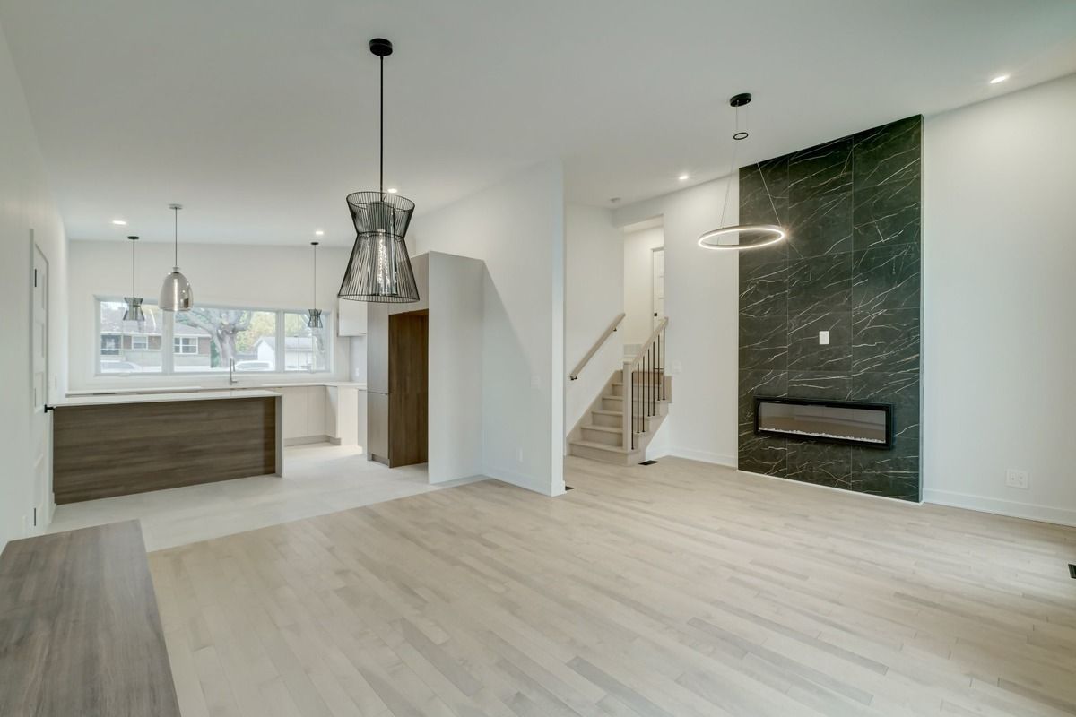 Un salon vide avec parquet et cheminée.