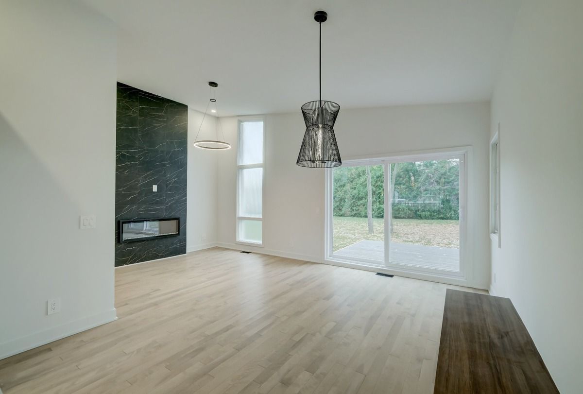 Un salon vide avec parquet et cheminée.