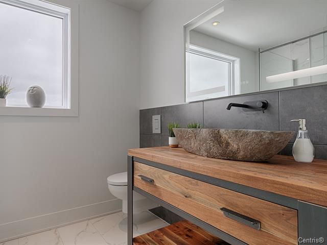 Une salle de bain avec lavabo , WC , miroir et fenêtre.