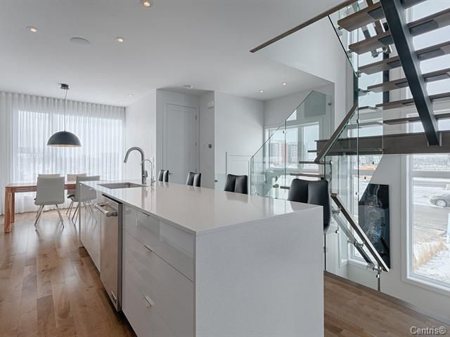 Une cuisine avec un grand îlot et des escaliers menant au deuxième étage.