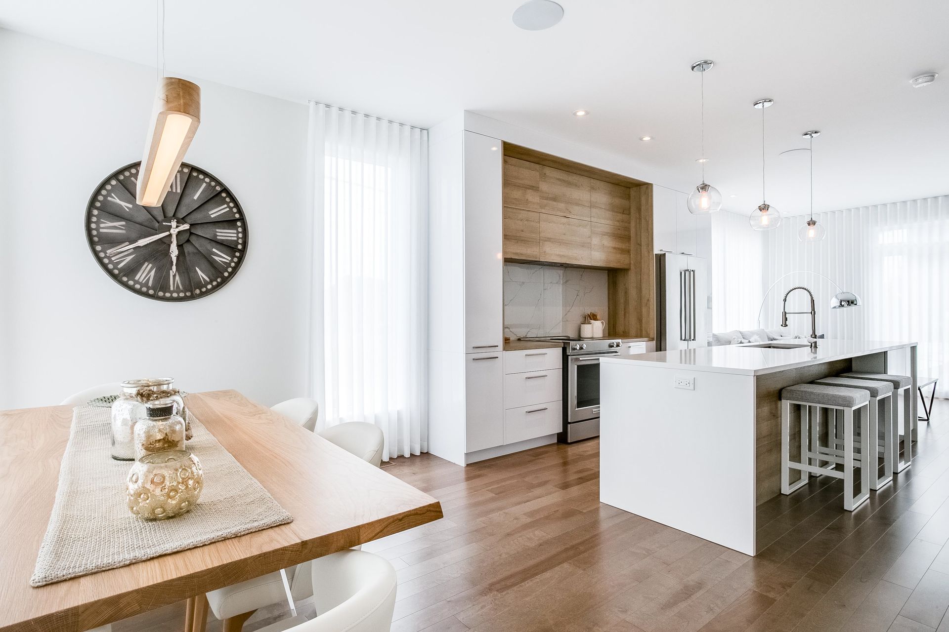 A kitchen and dining room in a house with a large clock on the wall.