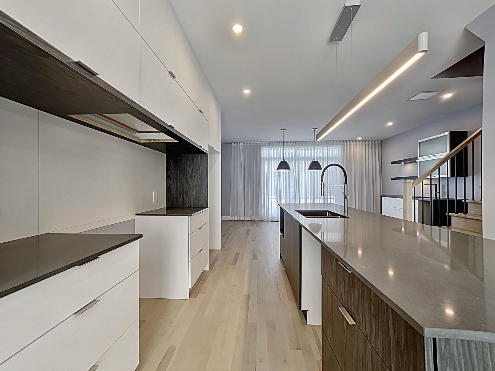 Une cuisine avec armoires blanches et un grand îlot au milieu