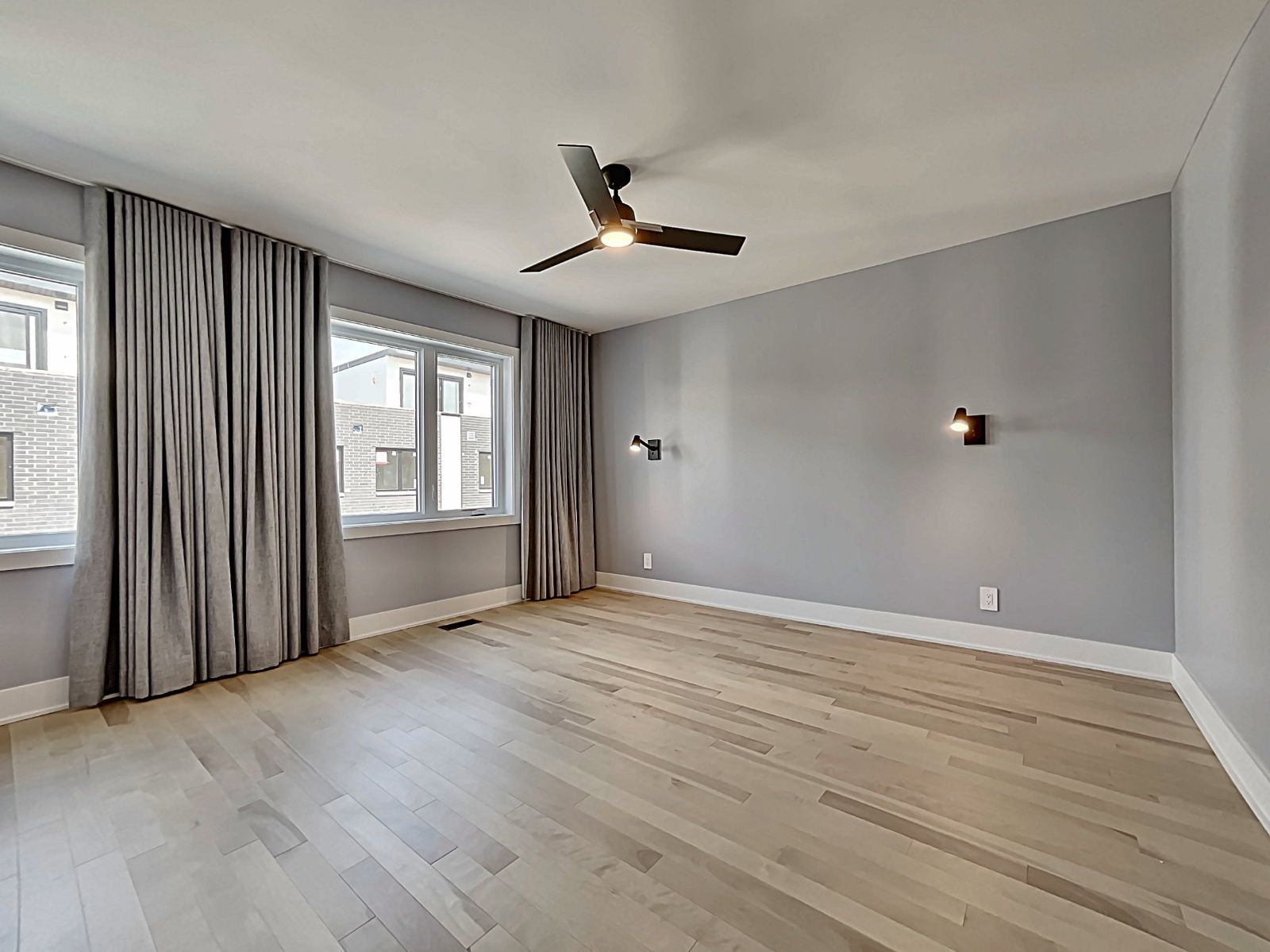 Une grande pièce vide avec du parquet et un ventilateur de plafond.