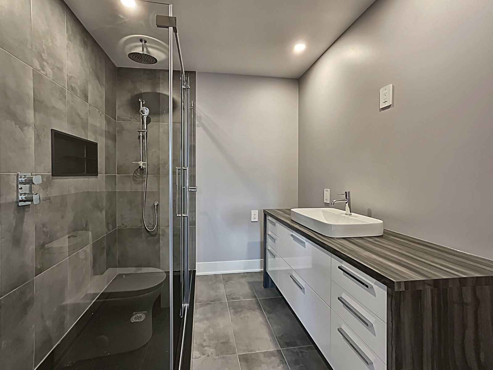 Une salle d'eau avec douche à l'italienne, lavabo et toilettes.