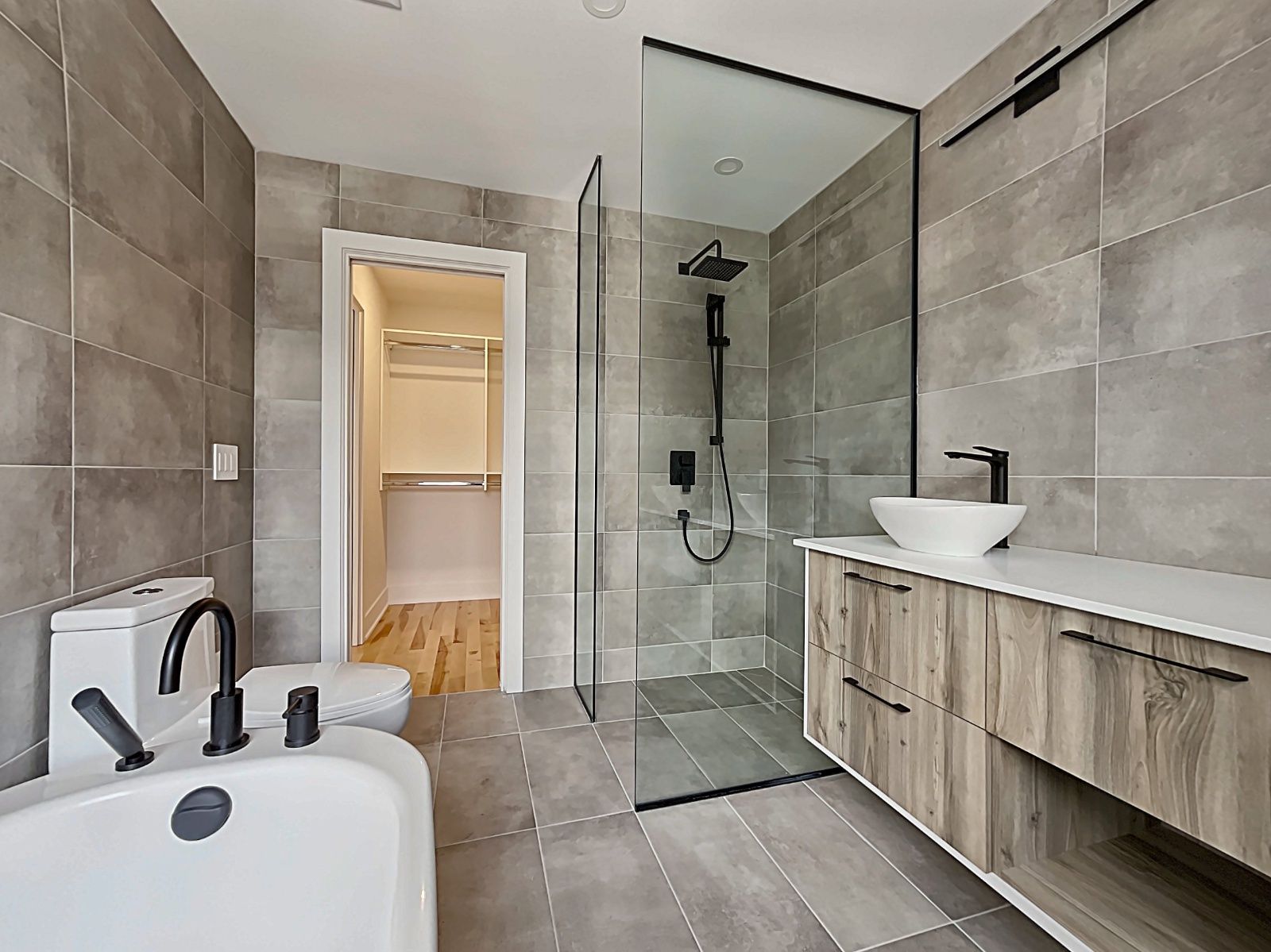 Une salle de bain avec baignoire, lavabo, toilettes et douche à l'italienne.