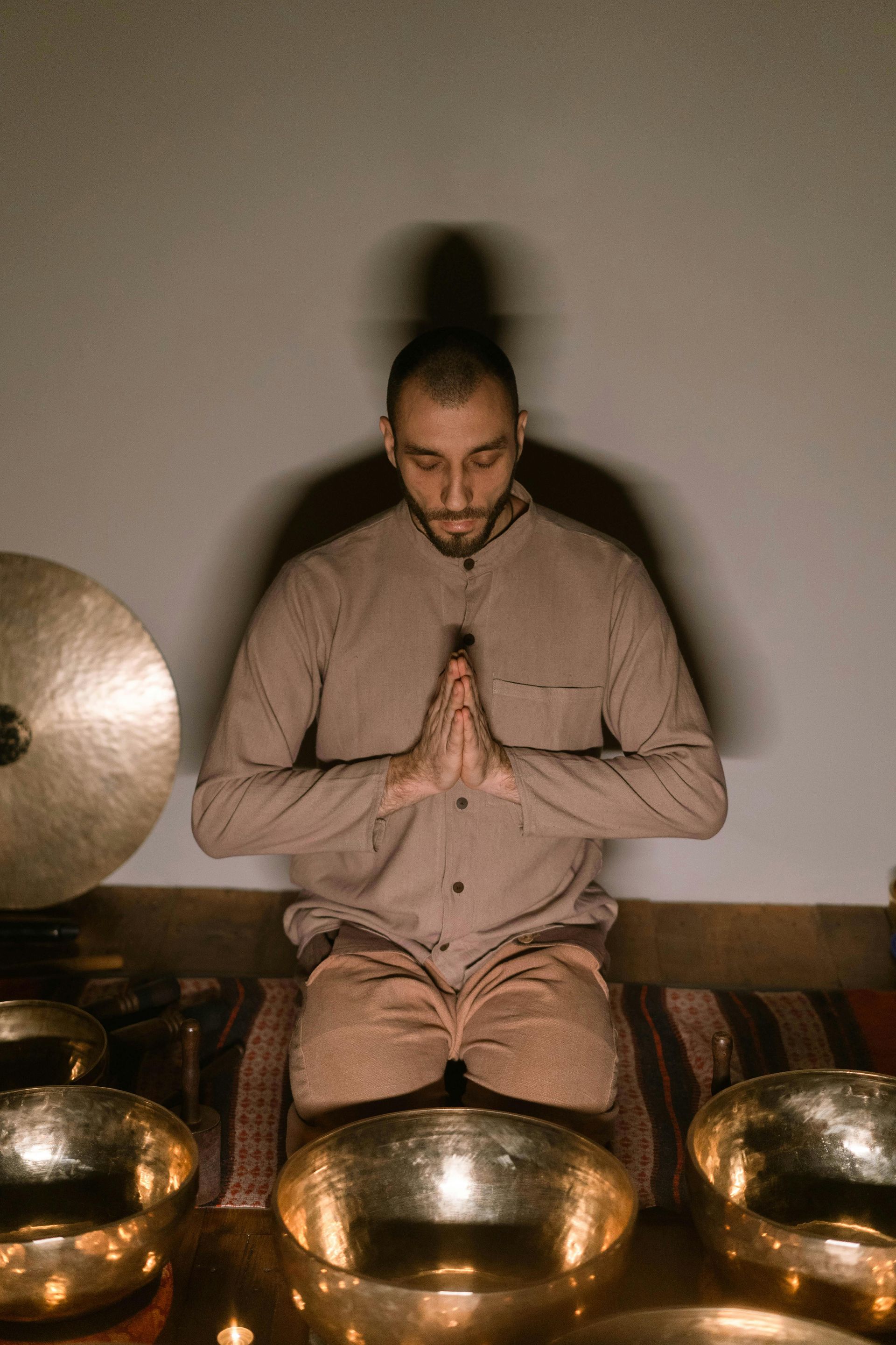 A man is sitting on the floor with his hands folded in prayer.