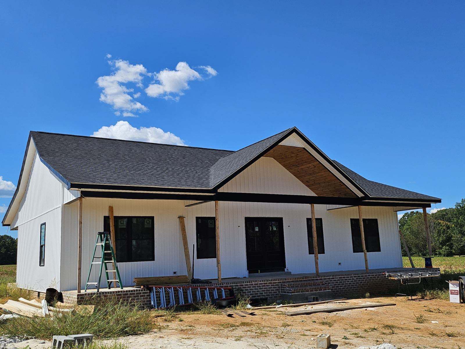 New white house under construction with a dark roof and blue sky overhead