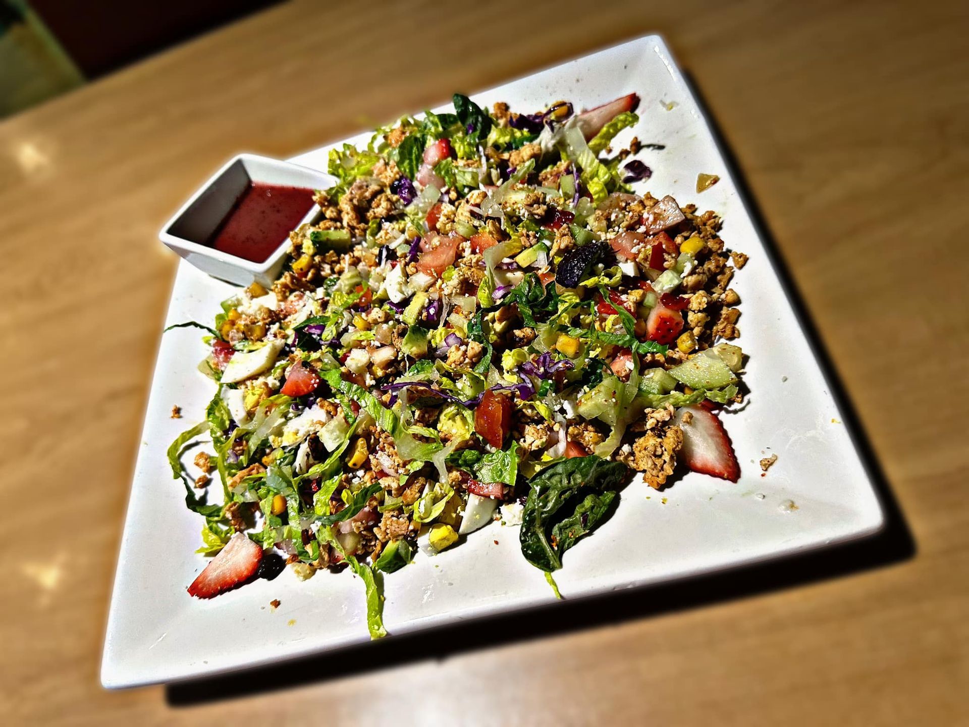 A salad with strawberries and spinach on a white plate