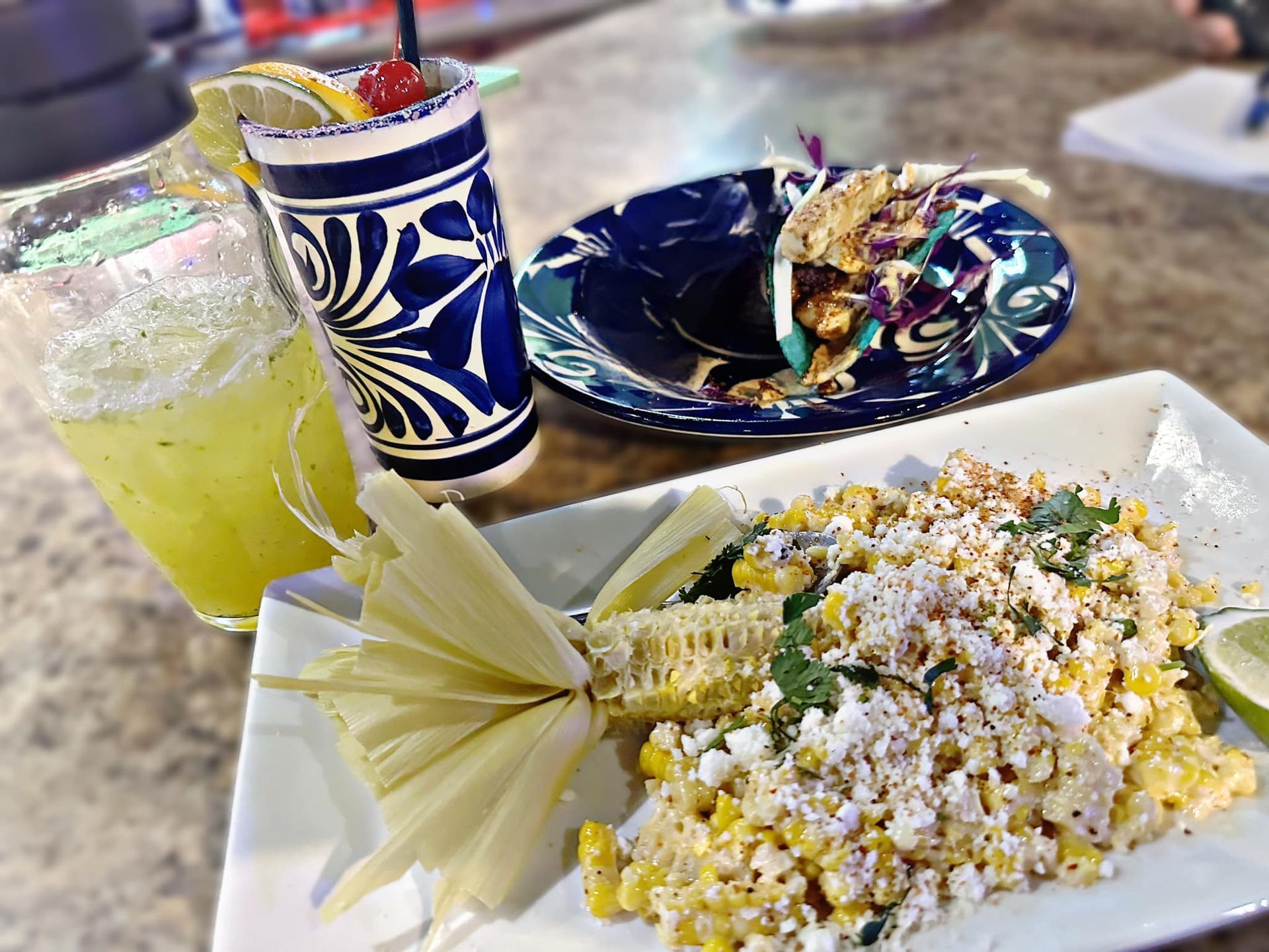 A plate of corn on the cob next to a drink on a table