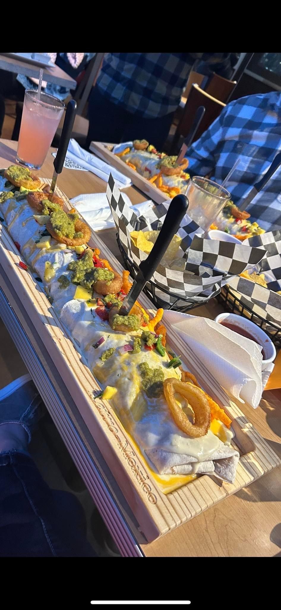 A long burrito with onion rings on top of it