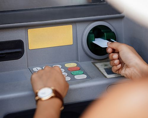 a person is inserting a credit card into an atm machine .