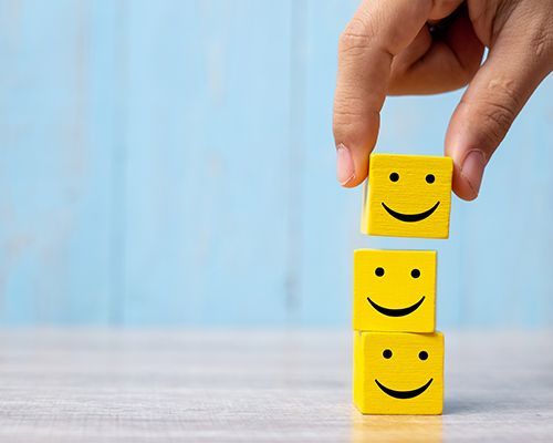 a person is stacking three wooden blocks with smiley faces on them .