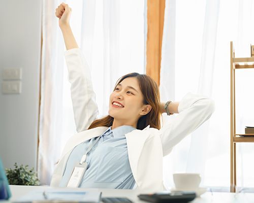 a woman is sitting at a desk with her arms outstretched .