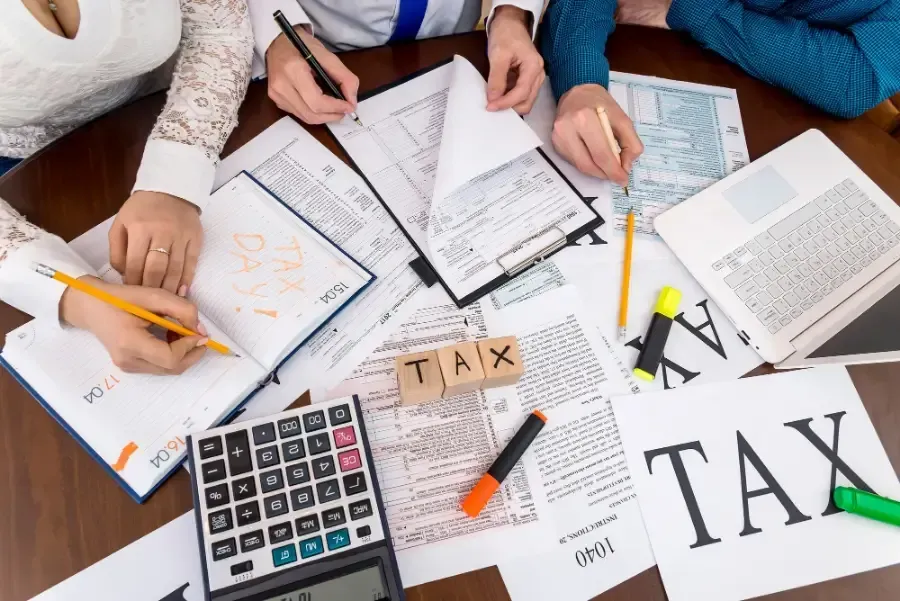 A group of people are sitting at a table with papers and a calculator.