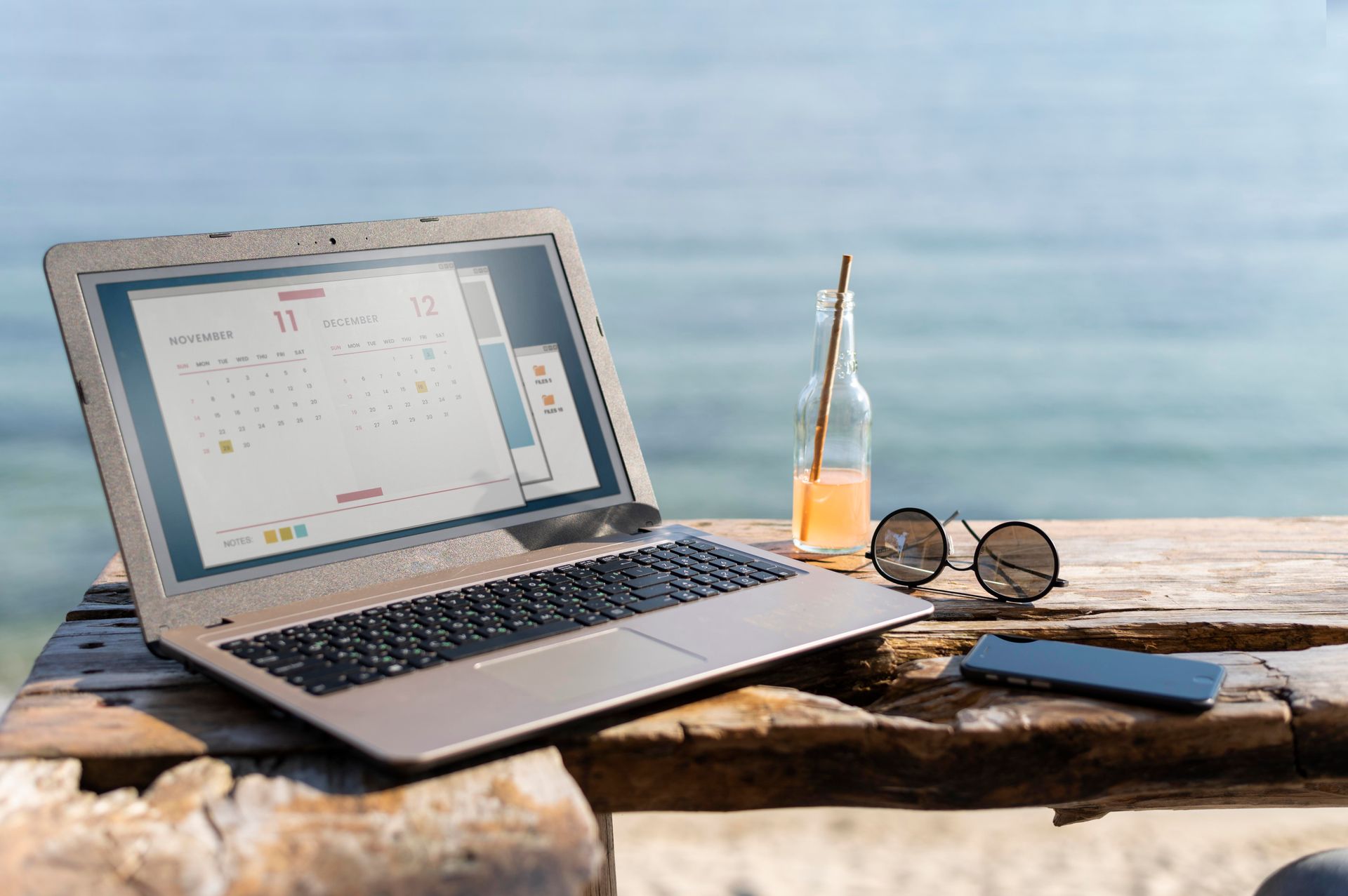 A laptop computer is sitting on a wooden table on the beach.