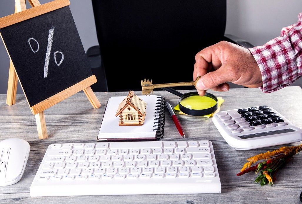 A person is holding a magnifying glass in front of a keyboard.