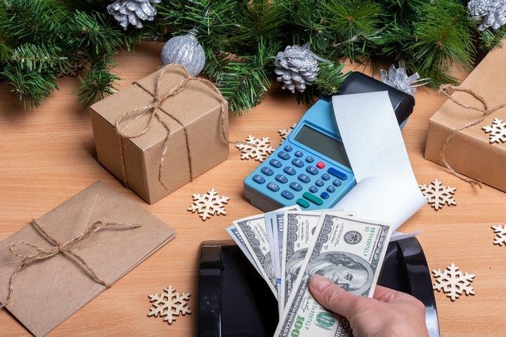 A person is holding a bunch of money in front of a calculator.