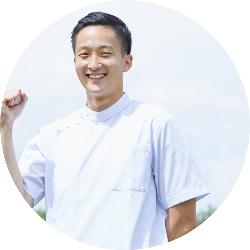 Smiling Asian man in white uniform, fist raised, outdoors.