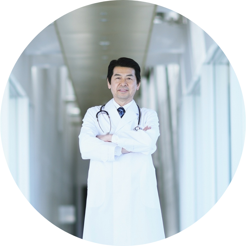 Asian doctor in white coat with crossed arms, standing in a bright hallway with a stethoscope.