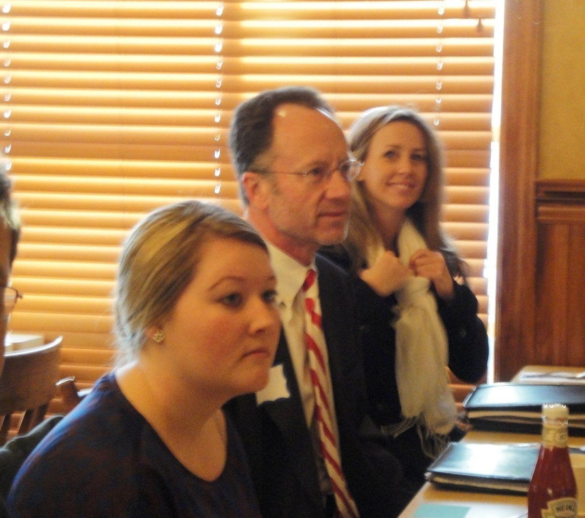 A group of people sitting at a table with a ketchup bottle in front of them