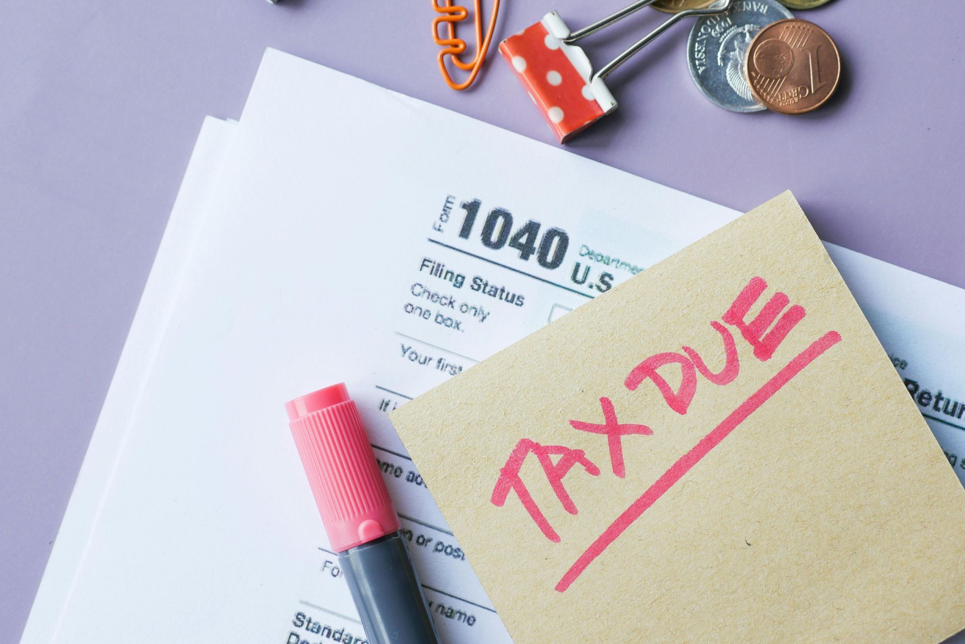 Tax paperwork with a pink sticky note reading “TAX TIME” and a marker on a desk