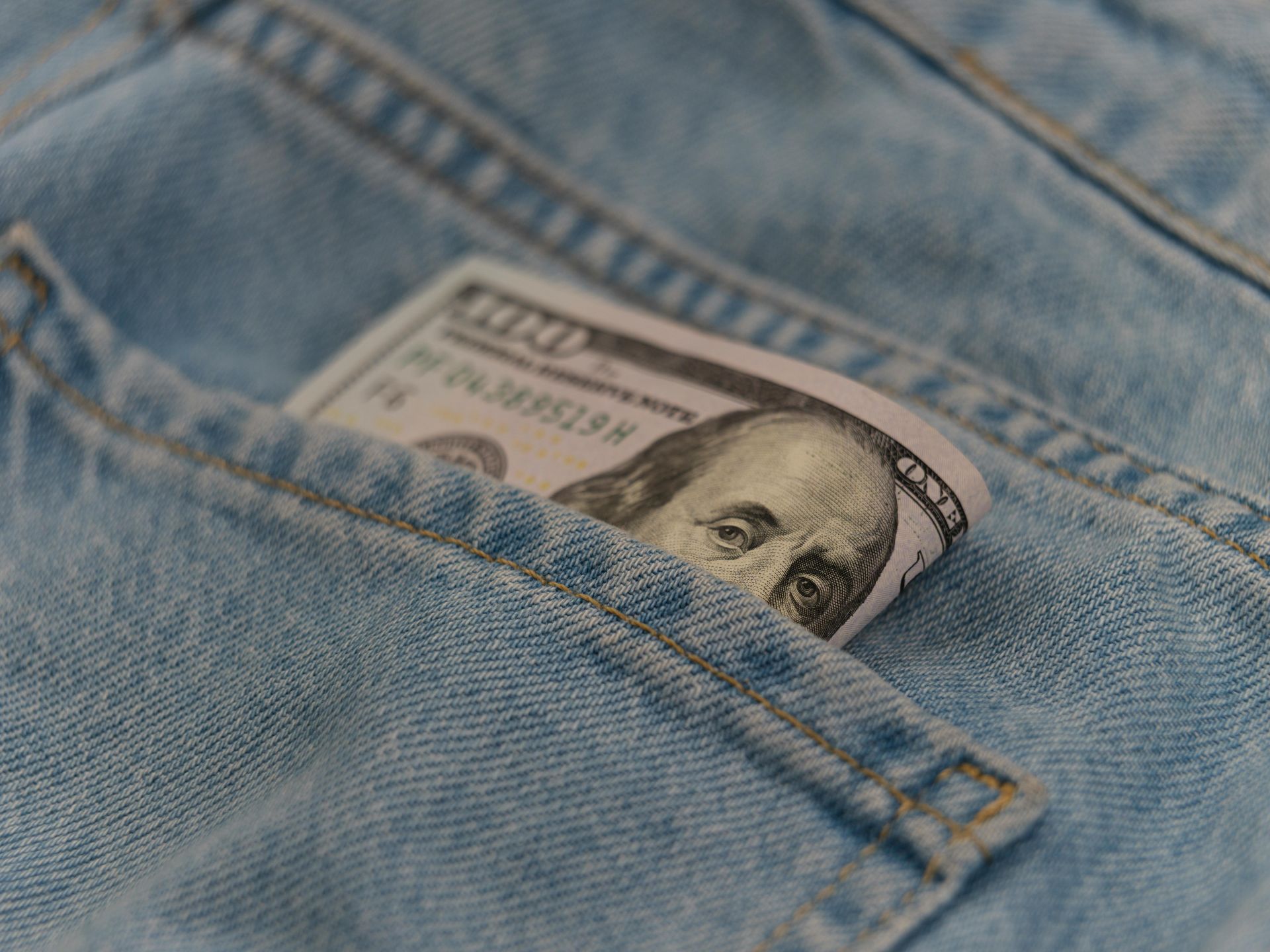 A rolled-up hundred-dollar bill tucked into the back pocket of blue denim jeans.