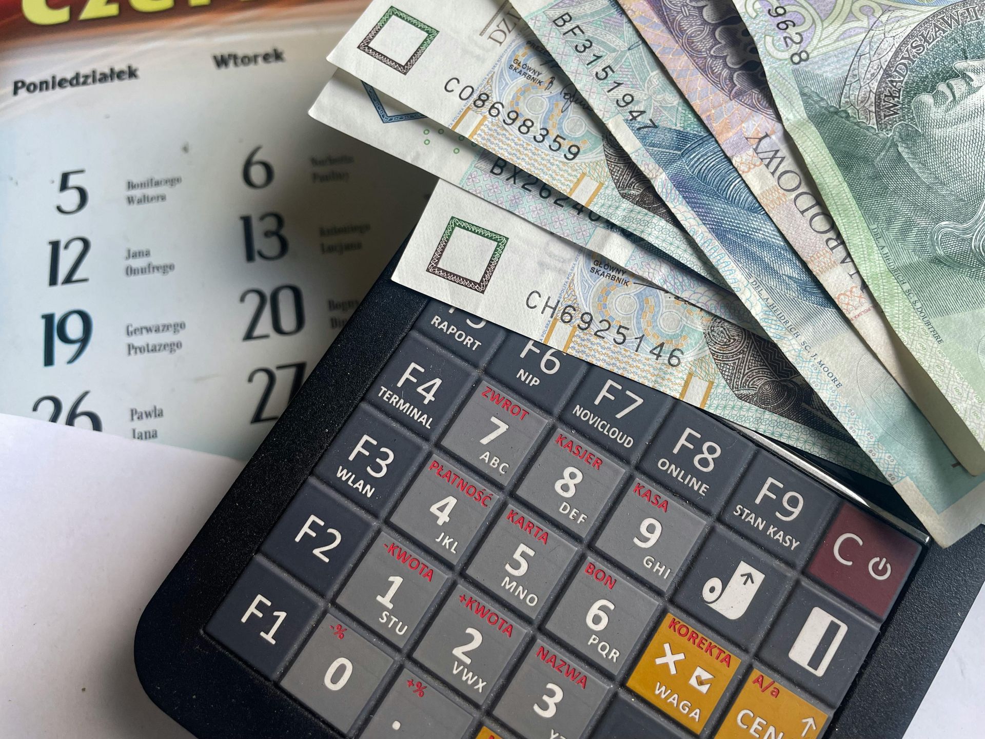 Calculator with Polish banknotes, next to a calendar, possibly related to finances or accounting.
