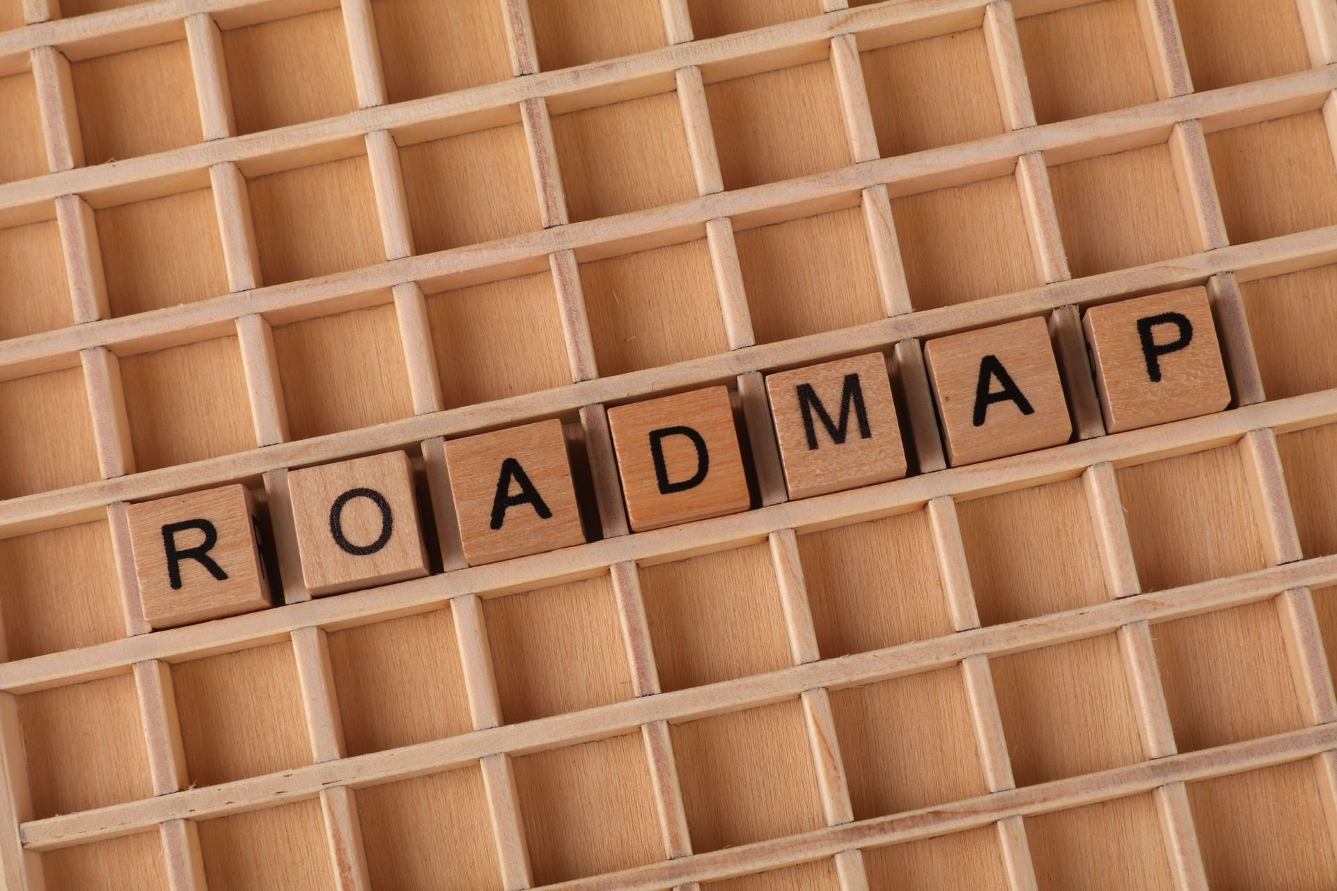 Scrabble tiles spelling “ROADMAP” on a wooden letter grid