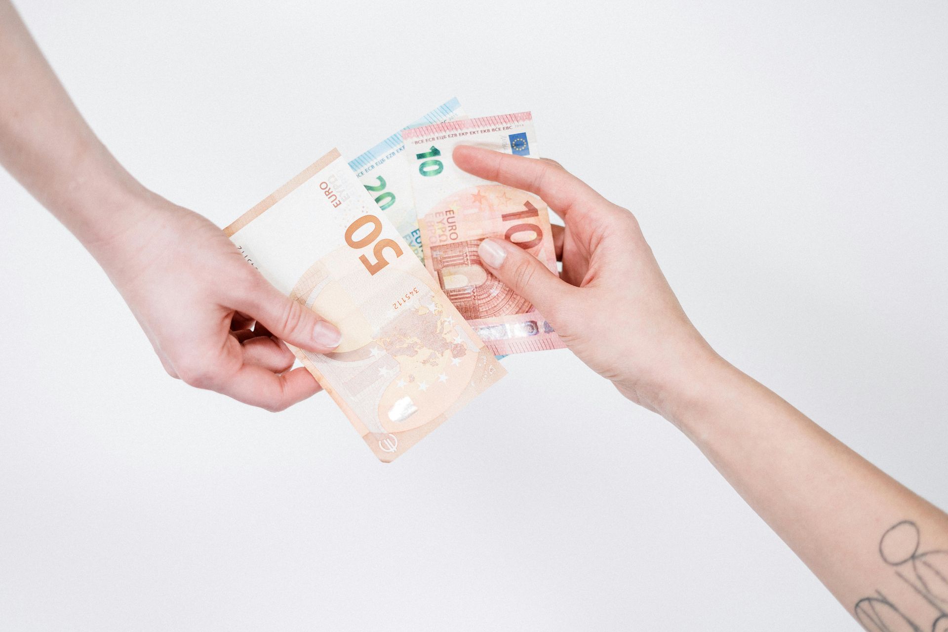 Hands exchanging euro banknotes on a white background. One hand offers, the other receives.