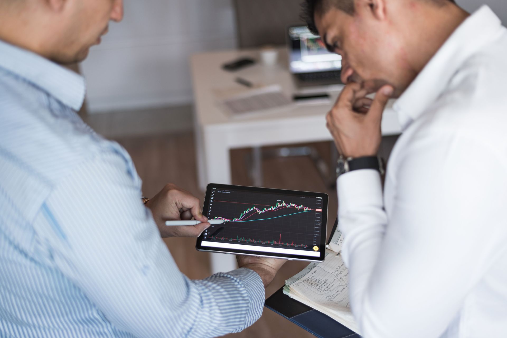 Two coworkers reviewing a tablet with a line chart in a meeting room