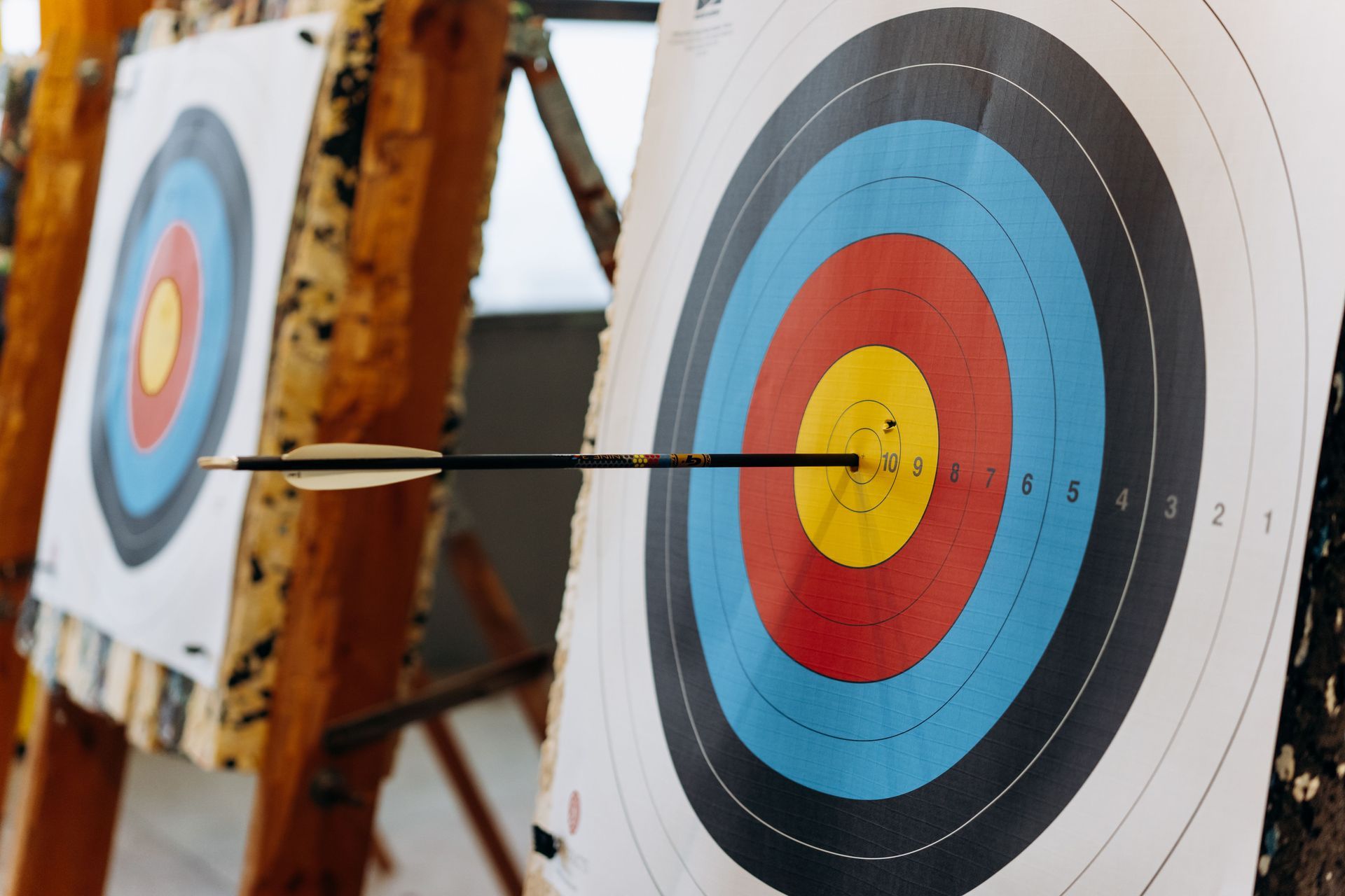 Arrows in a multicolored archery target, with one arrow hitting the yellow bullseye