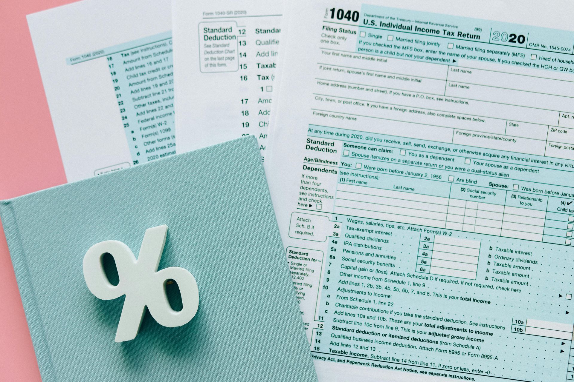 A book with a percent sign on it is sitting next to a tax form.