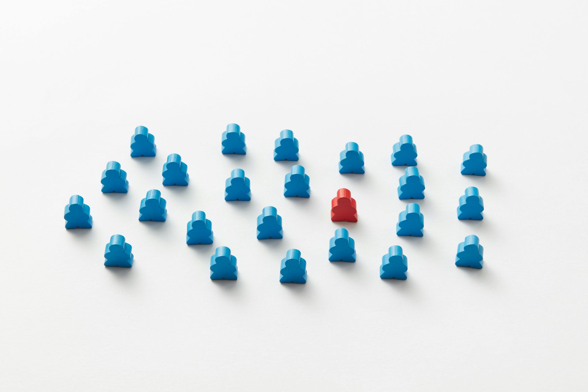 Blue wooden figures surround a single red figure on a white background.