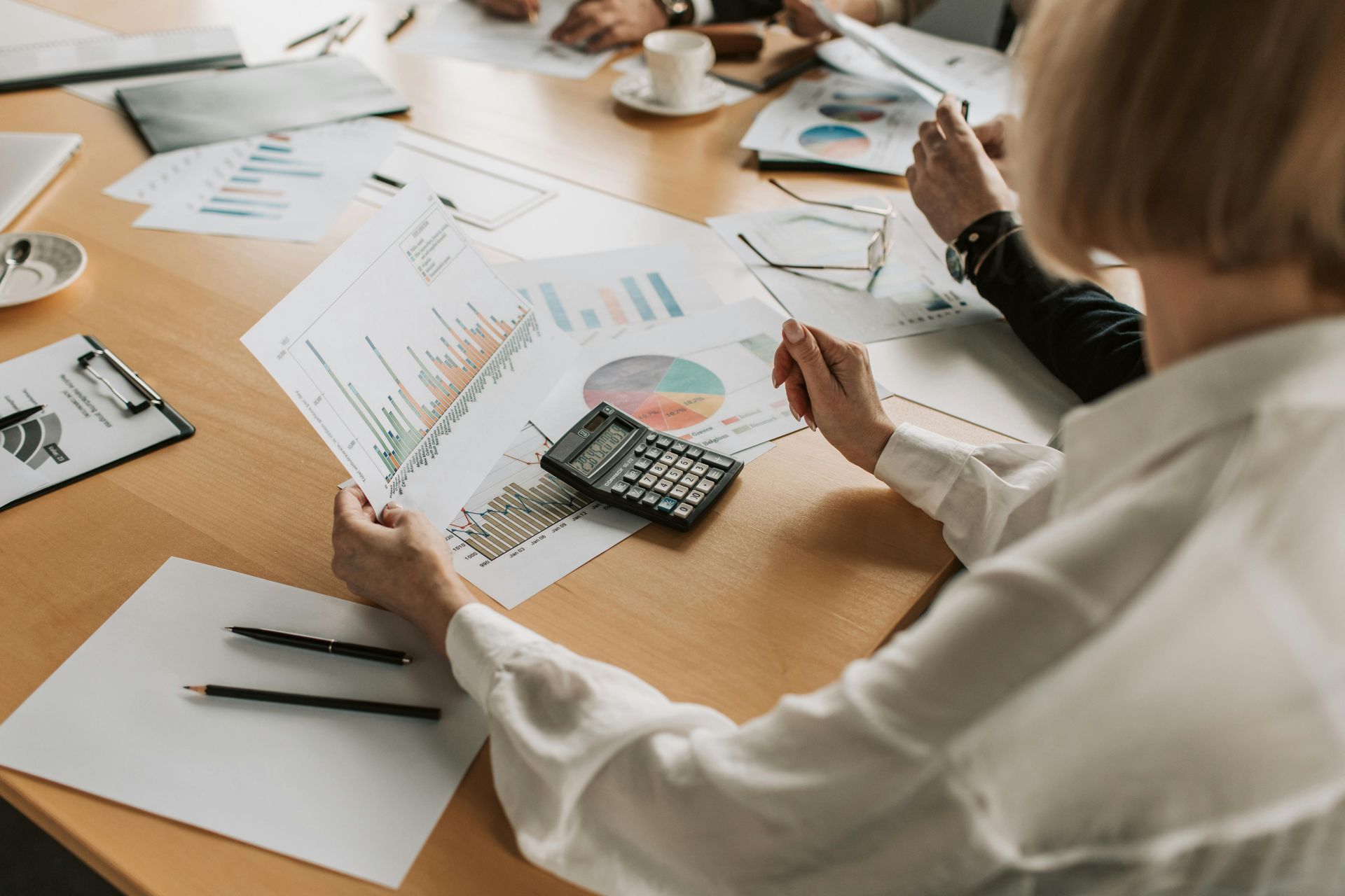Team reviewing charts and calculator during a business meeting at a conference table