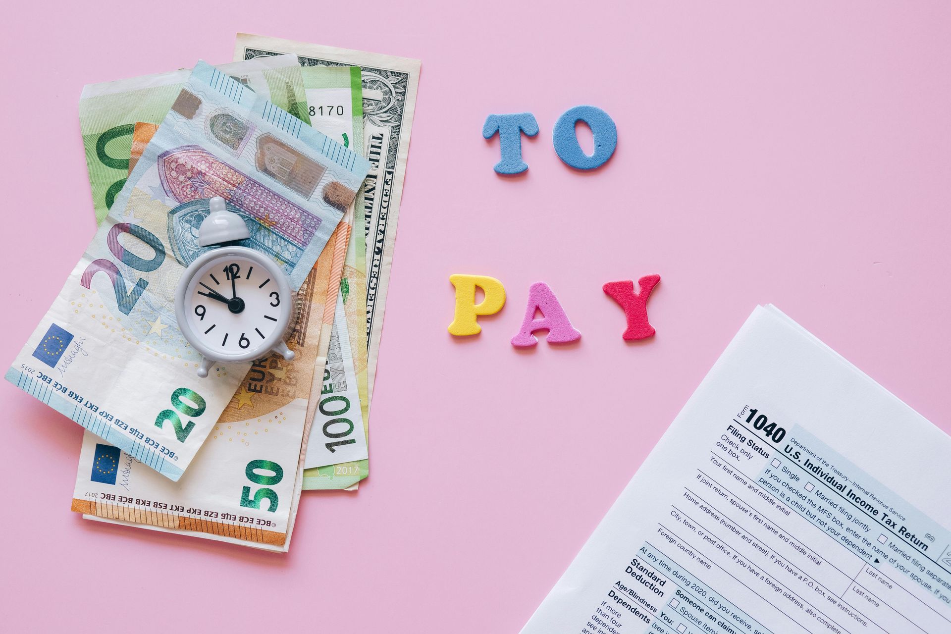Money, clock, and bill on pink background with the words “TO PAY”