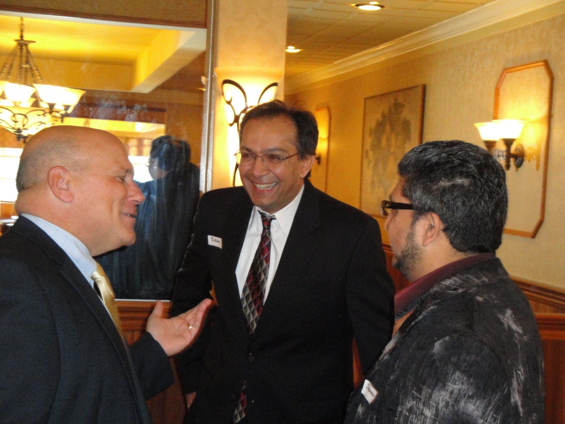 Three men in suits and ties are talking in a room